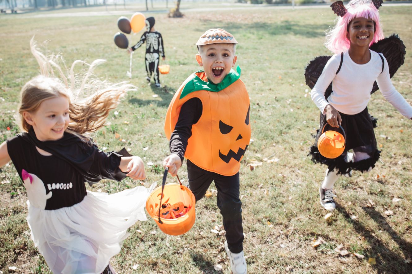 three young kids running toward camera dressed in halloween costumes
