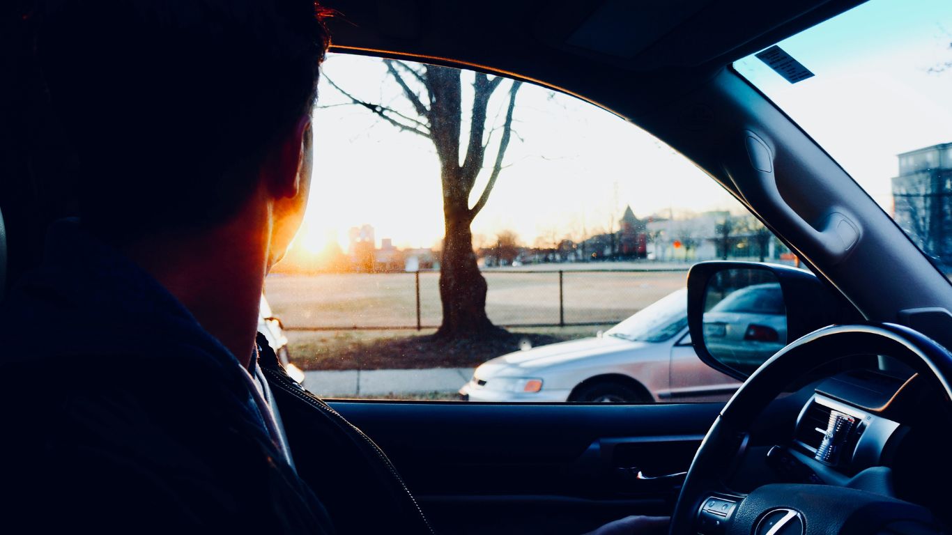 Man sits in car looking out the window.