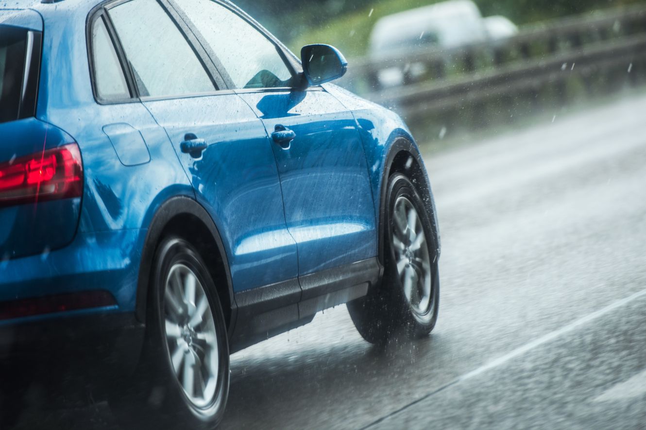 Blue car driving on highway in the rain