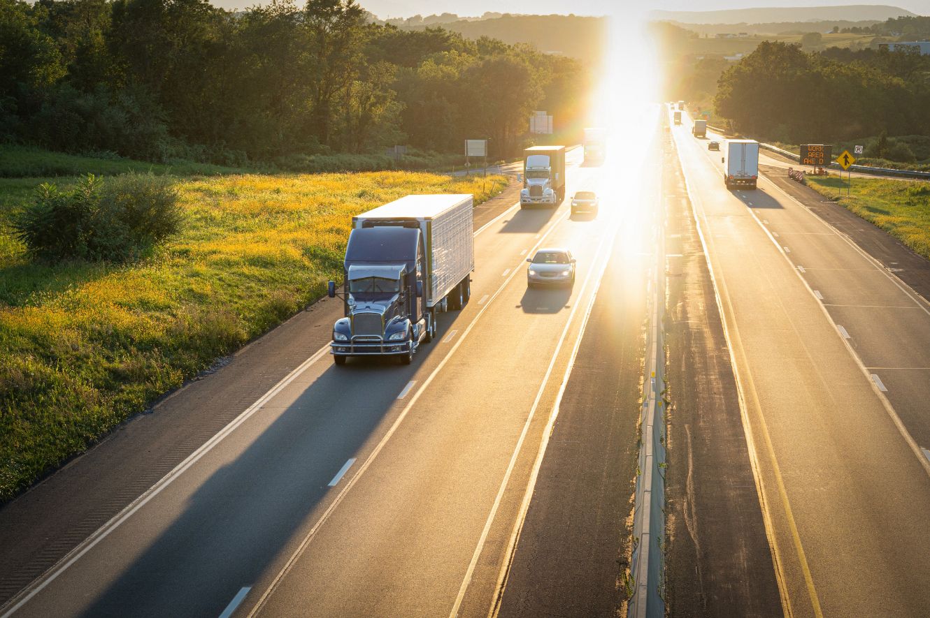 Drone image of a highway with cars and trucks driving toward the camera.