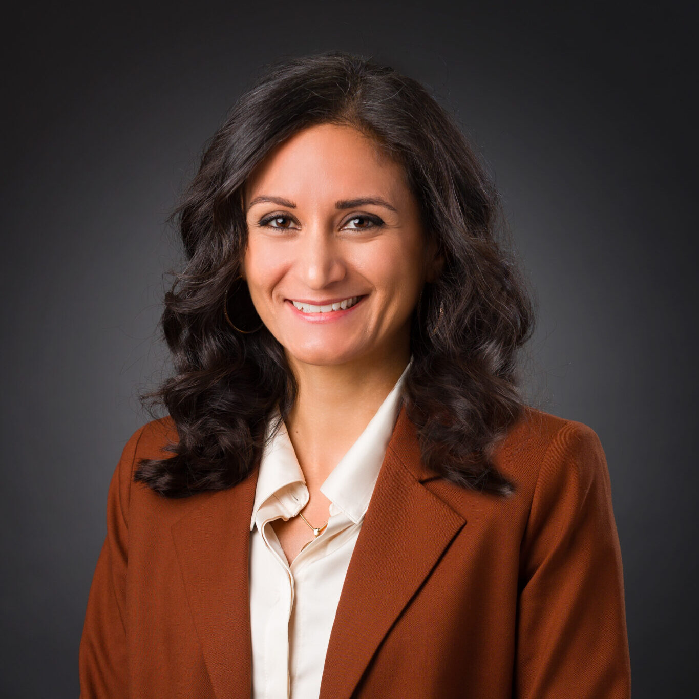 Portrait of Gina sitting against a dark background.