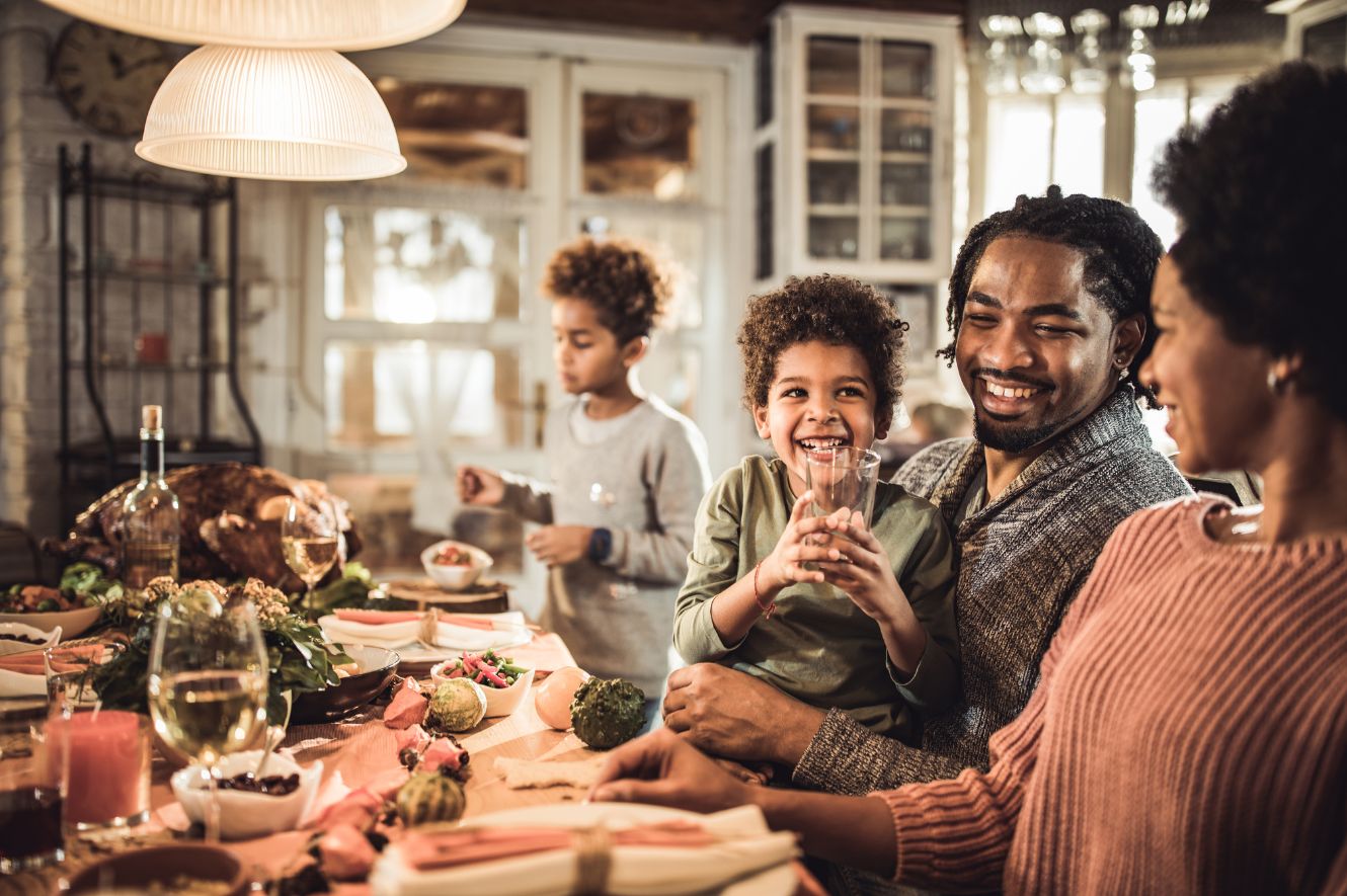 family sitting around the table eating a thanksgiving meal together.