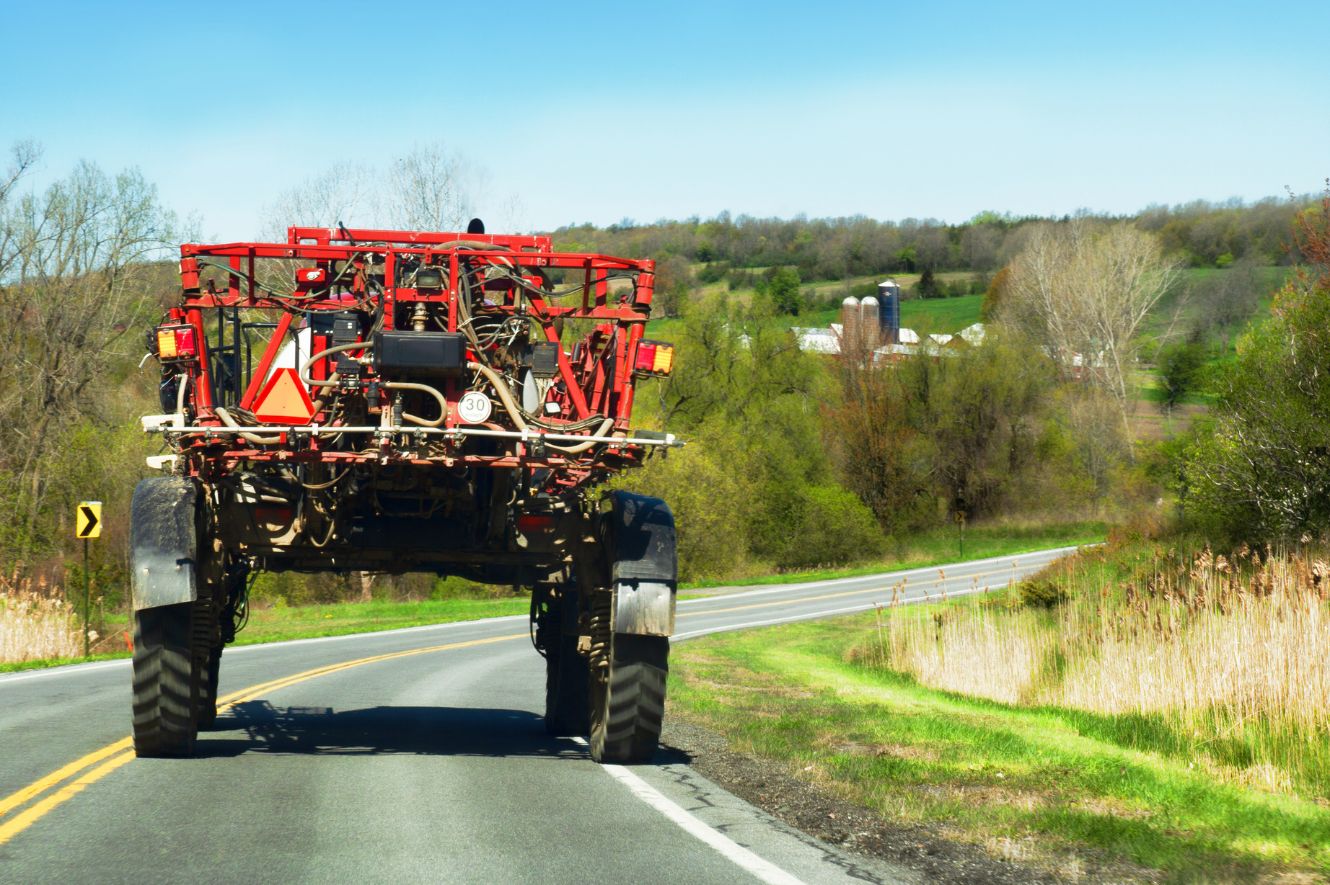 Crop Sprayer drives down a rural road during spring.