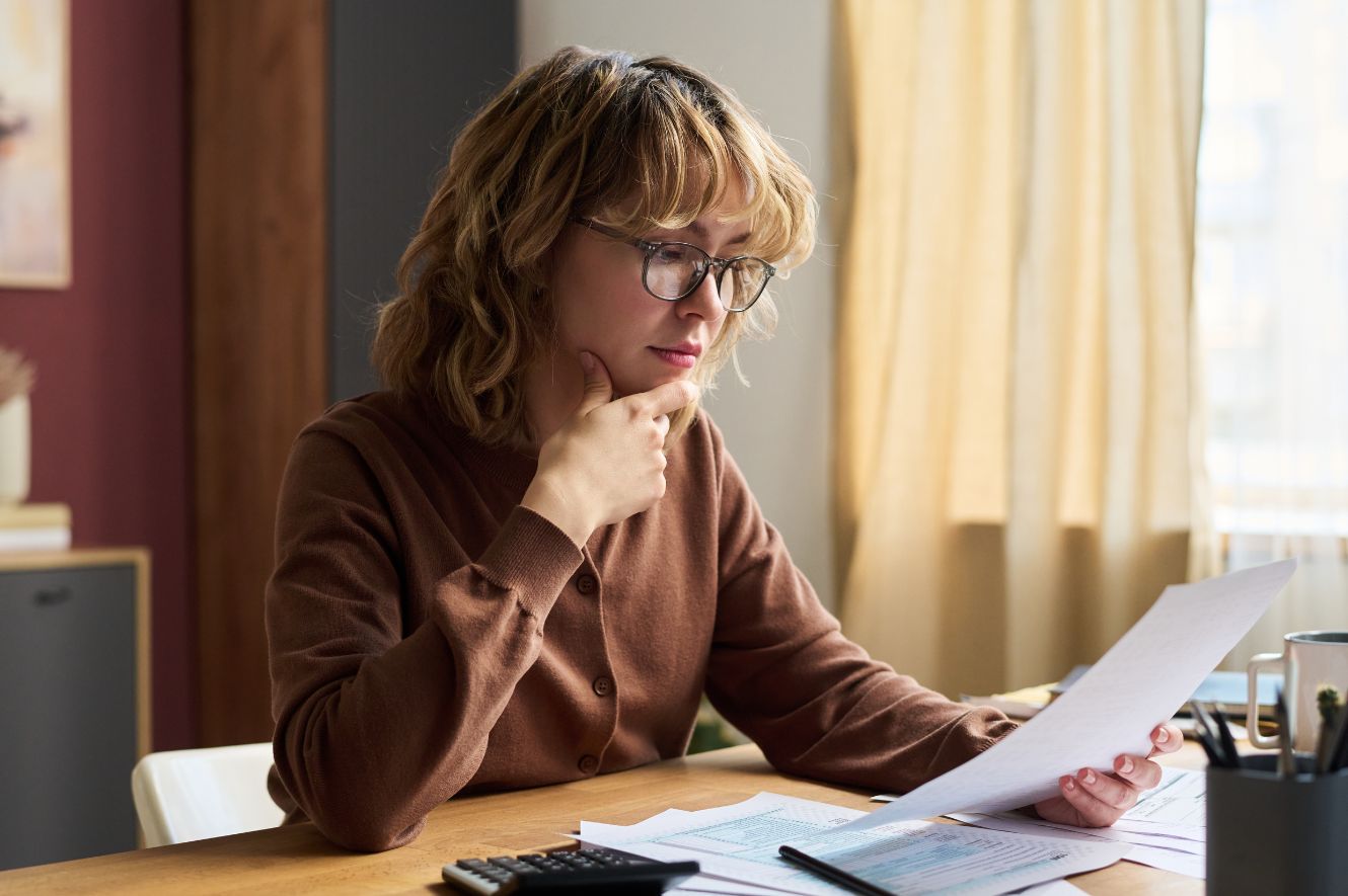 woman sits at desk looking thoughtfully at papers after receiving settlement check.