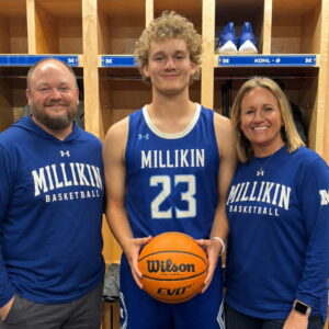 Scholarship winner Jacoby lane stands with his parents, wearing his millikin jersey and holding a basketball.